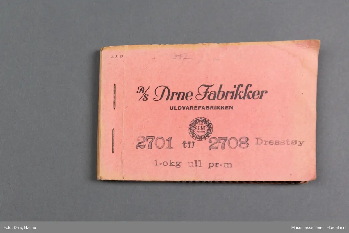 Mappe med rektangulære stoffprøver av vevd ullstoff frå ullvarefabrikken til Arne Fabrikker.