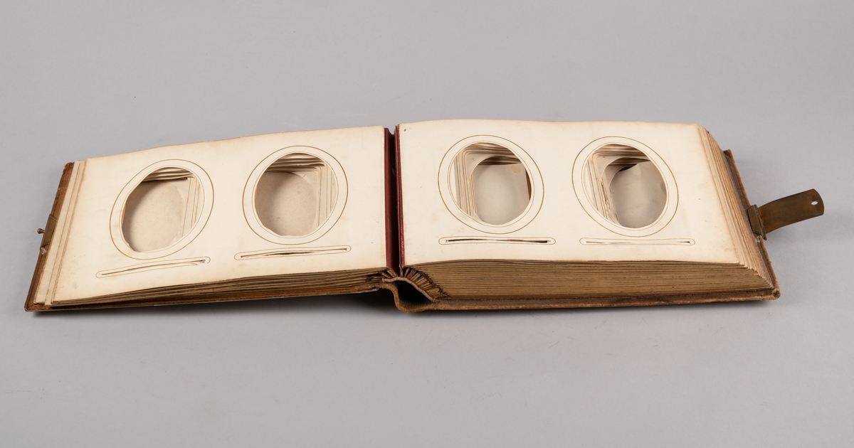 Rektangulært fotoalbum med forside dekket av perlemorsruter. Bakside av skinn. Lukkespenne i messing. Hver side med rom til to visittkortfoto.
