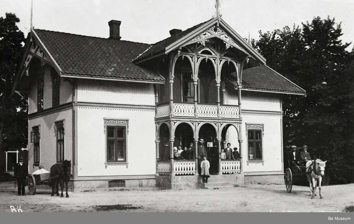 Åheim landhandel på Oterholt i Bø (nåv. Bø Museum) fotografert med folk og hestar framfor.