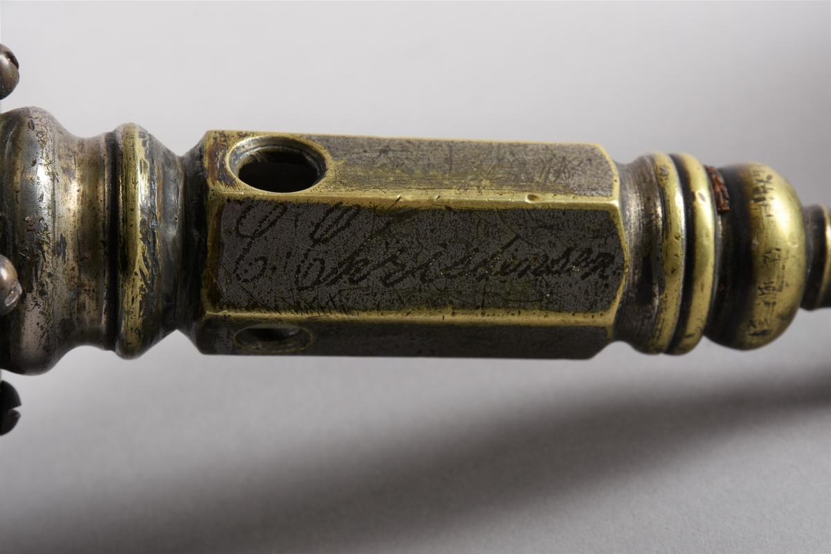 Sigarkutter/-kniv i to delar - ein kuttedel og ein behaldar.
Kuttedelen er eit sekskanta røyr med tre opningar av ulik storleik i nedste enden. På toppen av røyret eit stempel med fjøring og ein sylindrisk kuttekniv i andre enden. Kuttedelen er skrudd til ein sirkelrund base i tre som og fungerer som lokk over ein boks i dreid tre, til oppsamlig av avkutt frå sigarkniven. Sigaren settast inn i eit av dei tre hola, alt etter storleik, stempelet trykkast ned og kuttar tuppen av sigaren før bruk. Behaldaren er sylindrisk med profilkant på den øvre delen, med ein base med større diameter og profildreiing.