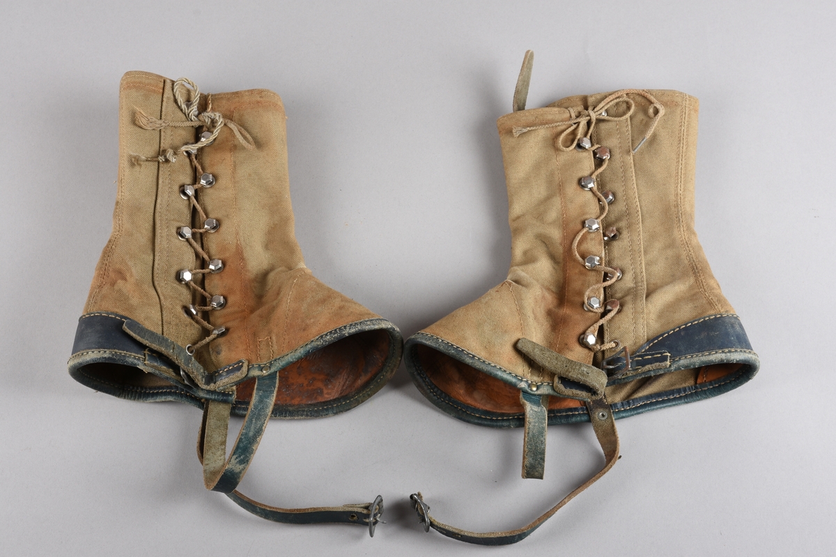 Eit par gamasjar for vaksne. Gamasjane er sydd i kraftig lerret. Påsydd naturfarga lêr besetning på innsida ved hæl- og tåparti  og over saumar. På utsida farga lêr på kanten nede, i hemper, reimer og som hælkappe.
Gamasjane har lukking på utsida med snor trædd gjennom seks par metall hekter og knytt oppe. I nedkant er og lukking med lêrstropp og metallspenne.