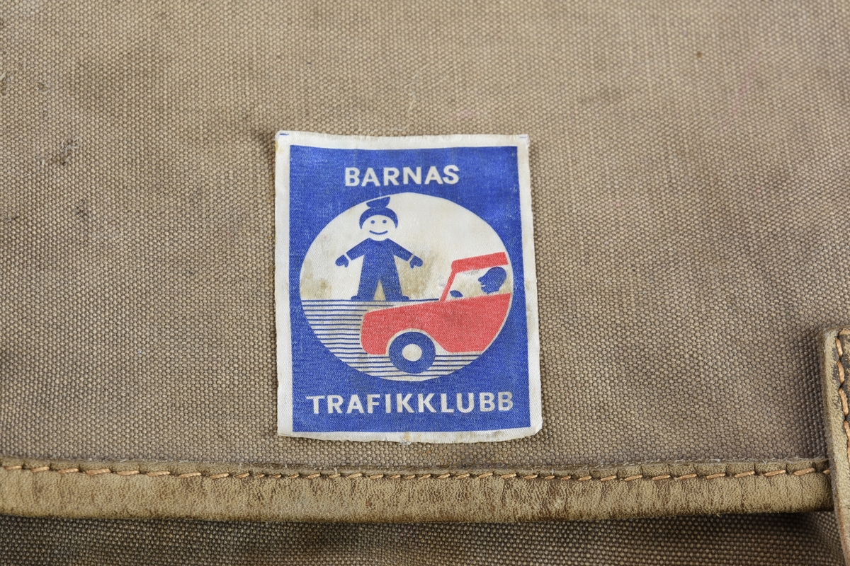 Ryggsekk for barn. Bakplata har rektangulær form. Sekken har to rom, det bakre rommet har opning i toppen, framrommet har glidelås i front. Lokket på sekken dekker begge romma når det er lagt på. Lokket har skinnkant og to skinnreimer for lukking med spenner festa i det framste rommet. Ryggselar i skinn er festa oppe på midten av ryggplata med skinnbeslag. På toppen av selefestet ei skinnhempe for oppheng. Selane kan regulerast på lengda og er festa med spenner nede på kvar side av ryggplata. Sekken er produsert i grov bomullslerret. Påsett merke på lokket.
