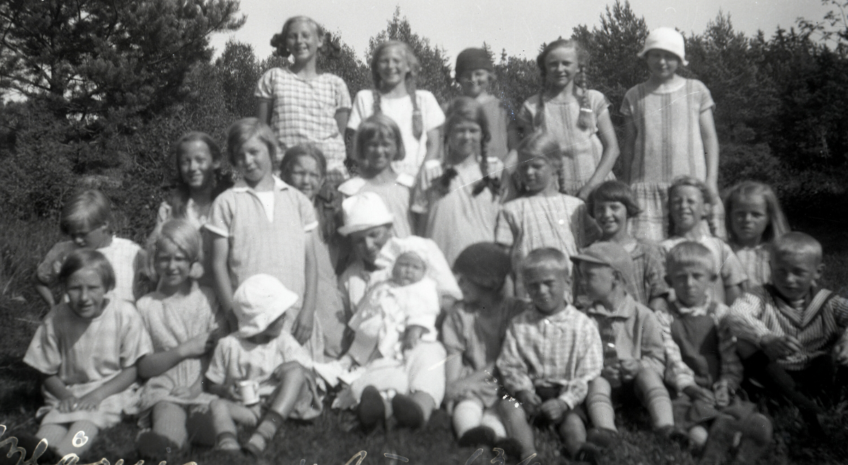Astrid Margrethe Terjesen med dotter Tordis og ei rekkje jenter rundt.  Tatt 26.7.1926