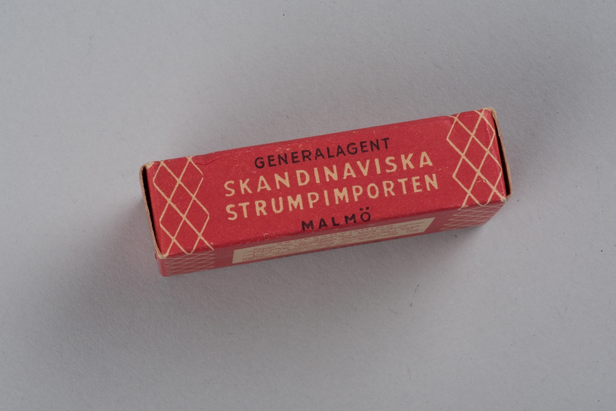 Tvål avsedd för tvätt av nylonstrumpor i originalförpackning. 
Tvålen består av gjuten tvålmassa med text i relief: NYLON SILKE. 
Pappersförpackningen är röd med rutmönster i beige och en tecknad silkesstrumpa i svart samt beige och svart text. På baksidan står en bruksanvisning.