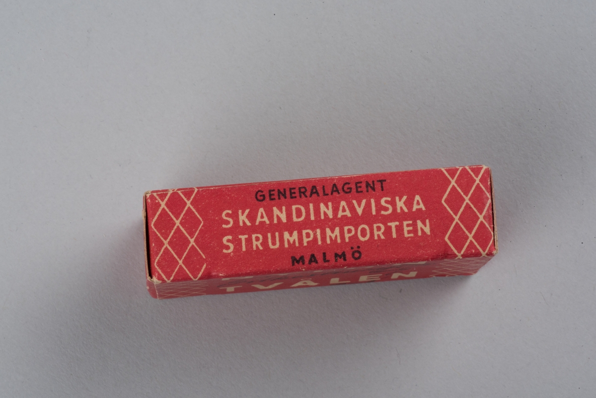 Tvål avsedd för tvätt av nylonstrumpor i originalförpackning. 
Tvålen består av gjuten tvålmassa med text i relief: NYLON SILKE. 
Pappersförpackningen är röd med rutmönster i beige och en tecknad silkesstrumpa i svart samt beige och svart text. På baksidan står en bruksanvisning.