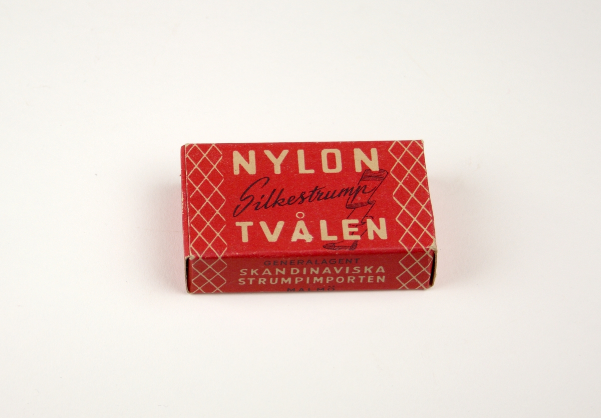 Tvål avsedd för tvätt av nylonstrumpor i originalförpackning. 
Tvålen består av gjuten tvålmassa med text i relief: NYLON SILKE. 
Pappersförpackningen är röd med rutmönster i beige och en tecknad silkesstrumpa i svart samt beige och svart text. På baksidan står en bruksanvisning.