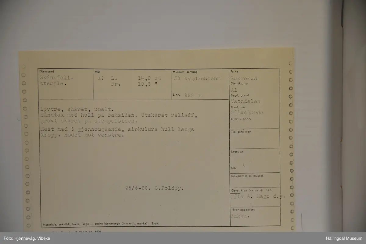 Håndtak med hull på baksiden. Utskåret relieff, grovt skåret på stempelsiden. Hest med 5 gjennomgående, sirkulære hull langs kropp. Hodet mot venstre.
25/6-68. O. Foldøy.