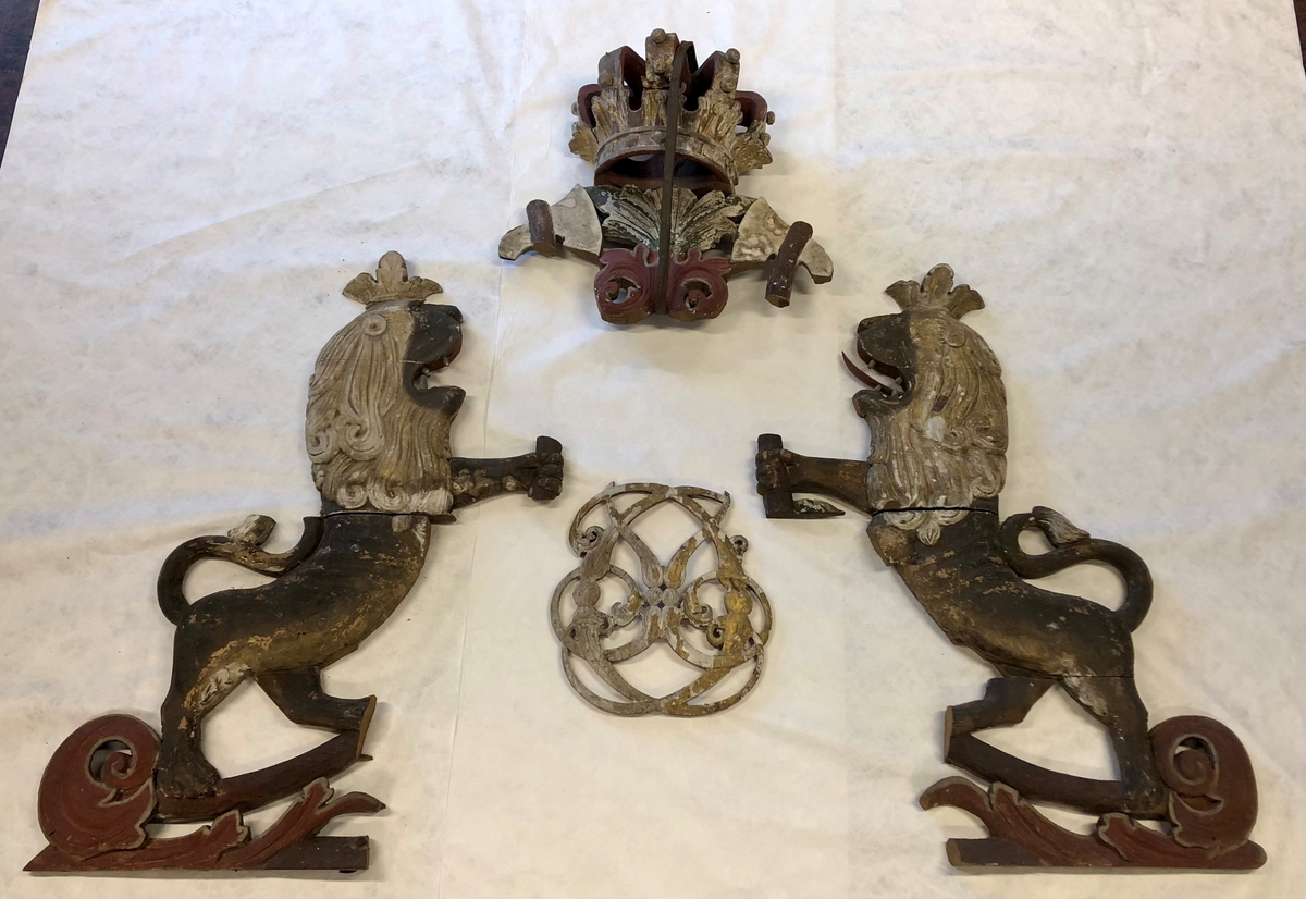 Korskille med to løvefigurer, en krone og et kongemonogram trolig til Christian den 6. (1730 - 1746).
Enkelte deler mangler, noe er saget av.
Løvefigur venstre side: I tre deler (krone, hode med arm og underkropp). Tunge og en tann mangler.
Løvefigur høyre side: I tre deler (hode med krone og arm, overkropp og underkropp delt). 
Krone med to hellebarder på hver side som skal henge sammen med løvefigurene. Spydene på toppen av øksehodene mangler. Kronen er holdt sammen et jernbånd som har vært festet til korskillet. En del på kronen er løs.
Kongemonogrammet er løst.
