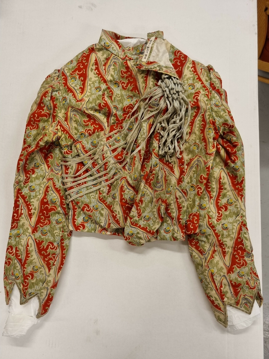 Jakke: Halslinning, lange ermer, forknappet,spiler,smale fløyelsbånd til pynt. Foret.

Skjørt: Linning, volang, foret.