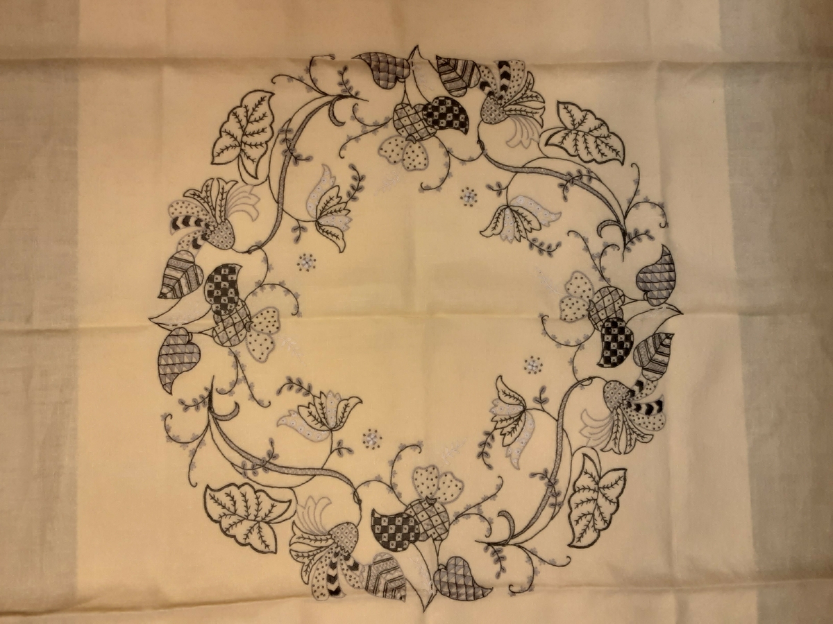 Duken er av lin eller halvlin og brodert med broderigarn sannsynligvis av bomull i ulike nyanser av sort og grått.