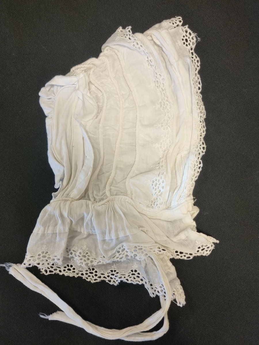 Kysefasong med knytesnor under haken. Legg, bisesømmer, kapper og blonder.