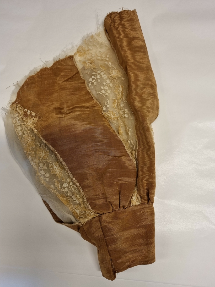 Kort erme med linning og god vidde. I silkerips og kniplinger. Organza fòr.