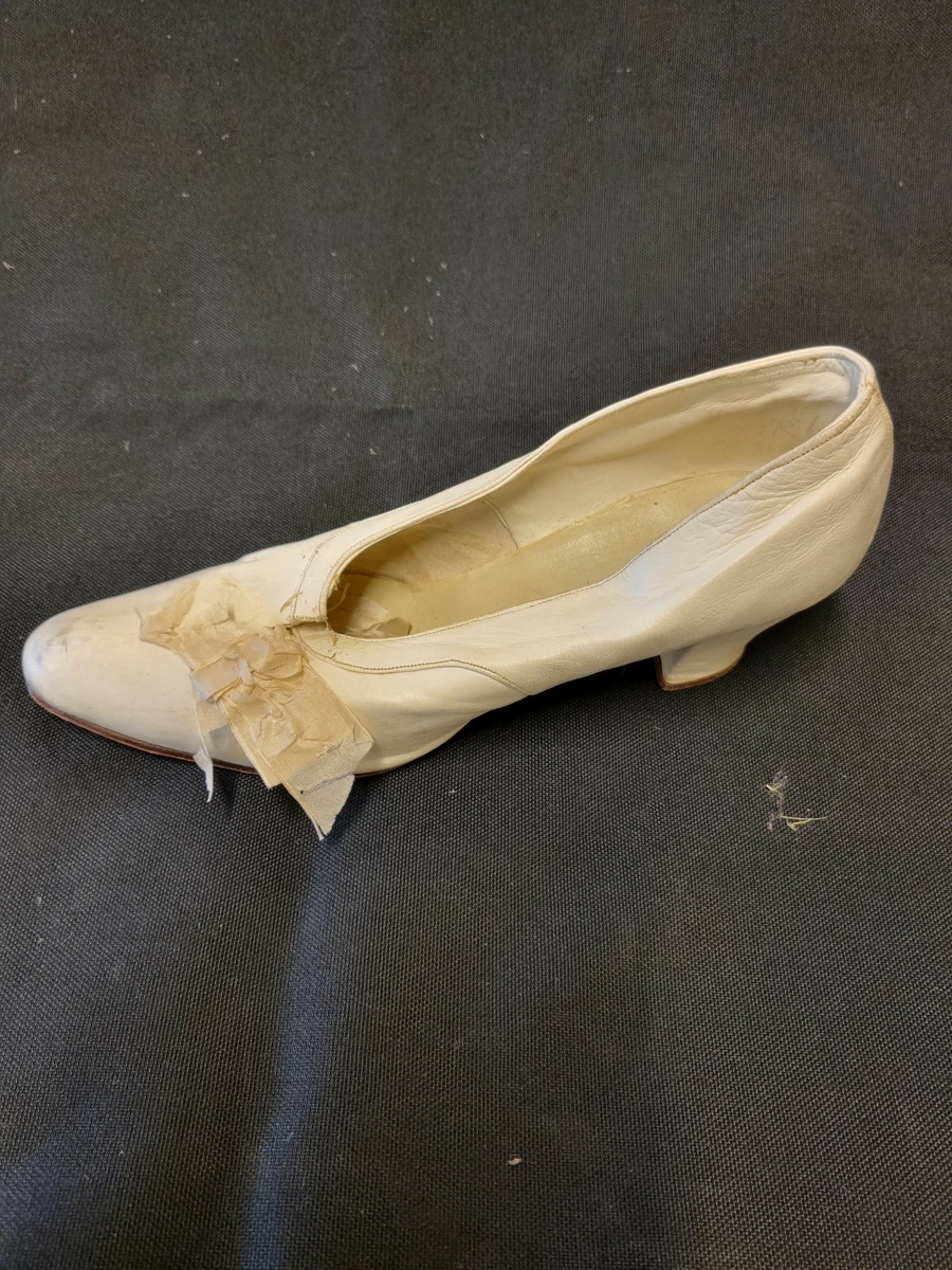 En brudesko av typen skinnpumps med snellehæl. Skinnforet og dekorert med en liten sløyfe.