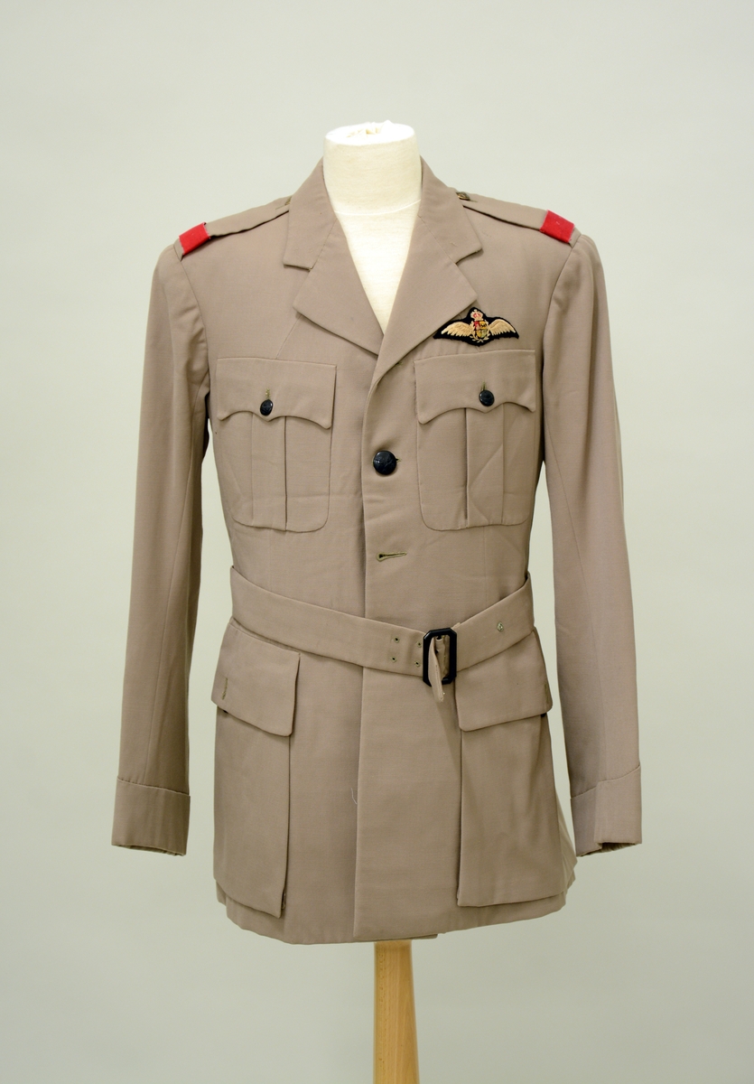 A.Uniformsjakke. Tropeuniform. Beige jakke i syntetisk materiale med 4 lommer foran. 8 knapper med emblem, skulderklaffene med rødt merke uten distinksjoner. Påsydd flygersymbolmerke foran. Jakken har fôr i armene og ved nakkepartiet. Belte med beltespenne.

B. Uniformslue. Luen har en brett festet med trykk-knapp på begge sider. Denne bretten kan brettes ut, og det blir en lue som kan festes under haken med to små knapper med emblem. Innvendig er det svettebånd og fôr.