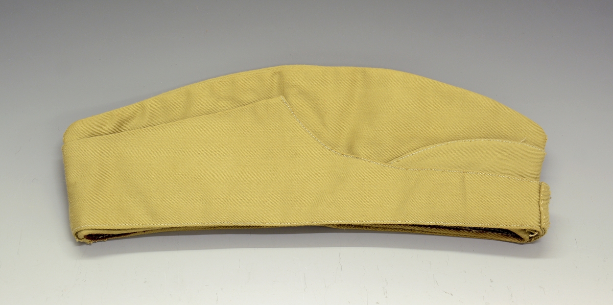 A.Uniformsjakke. Tropeuniform. Beige jakke i syntetisk materiale med 4 lommer foran. 8 knapper med emblem, skulderklaffene med rødt merke uten distinksjoner. Påsydd flygersymbolmerke foran. Jakken har fôr i armene og ved nakkepartiet. Belte med beltespenne.

B. Uniformslue. Luen har en brett festet med trykk-knapp på begge sider. Denne bretten kan brettes ut, og det blir en lue som kan festes under haken med to små knapper med emblem. Innvendig er det svettebånd og fôr.