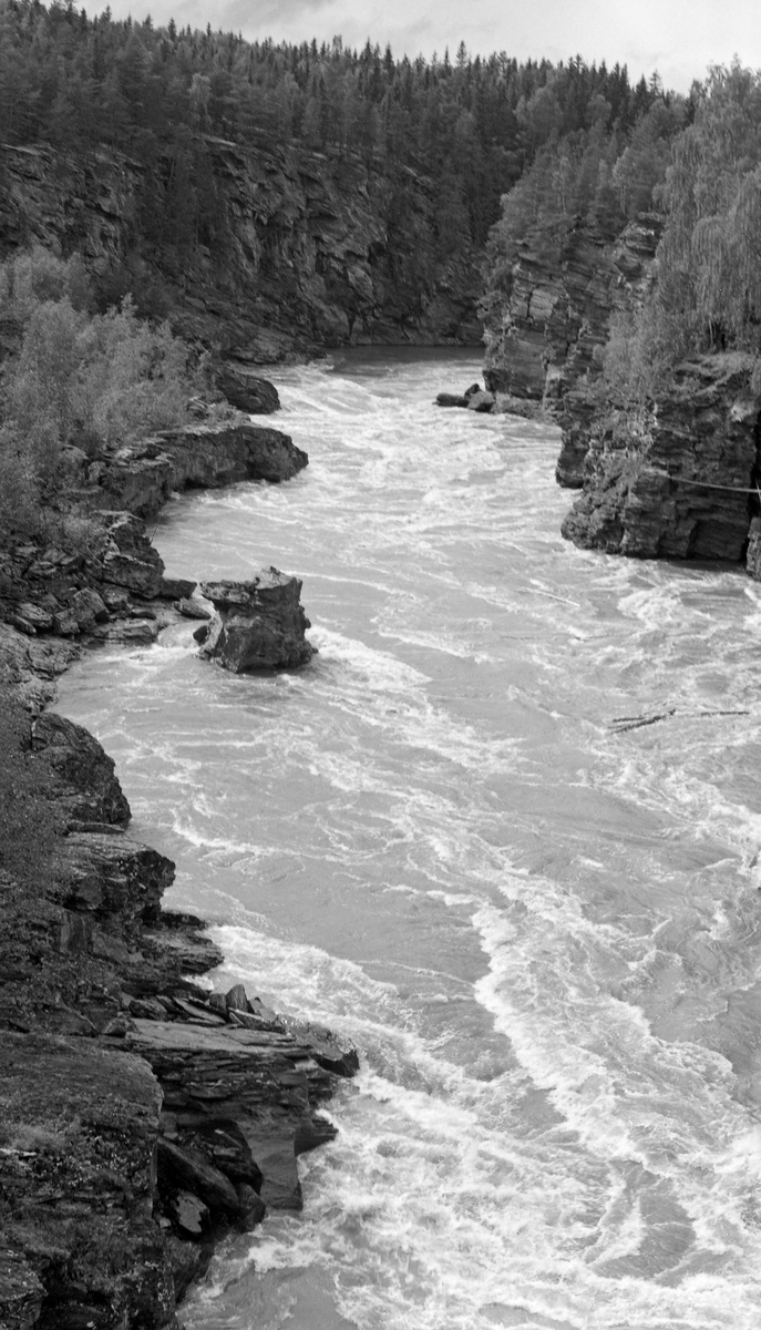 Den øvre delen av Harpefossen i Gudbrandsdalslågen, fotografert fra vestre elvebredd, men i medstrøms retning, slik elveløpet så ut like før fossen ble regulert i begynnelsen av 1960-åra. Dette er antakelig det som kaltes Solbråfossen, etter garden som ligger på østre elvebredd, ved innløpet til det cirka 1 kilometer lange elvegjeldet med cirka 25 meters fall. Som vi aner smalner elveløpet nedover, etter hvert til bare 15-20 meters bredde.  Bergskrentene langs elva var bratte og strømmen var strid, så dette var absolutt en flaskehals for fløtinga i Lågen. På dette fotografiet kan vi ane enkelte tømmerstrokker i det kvitskummende vannet.