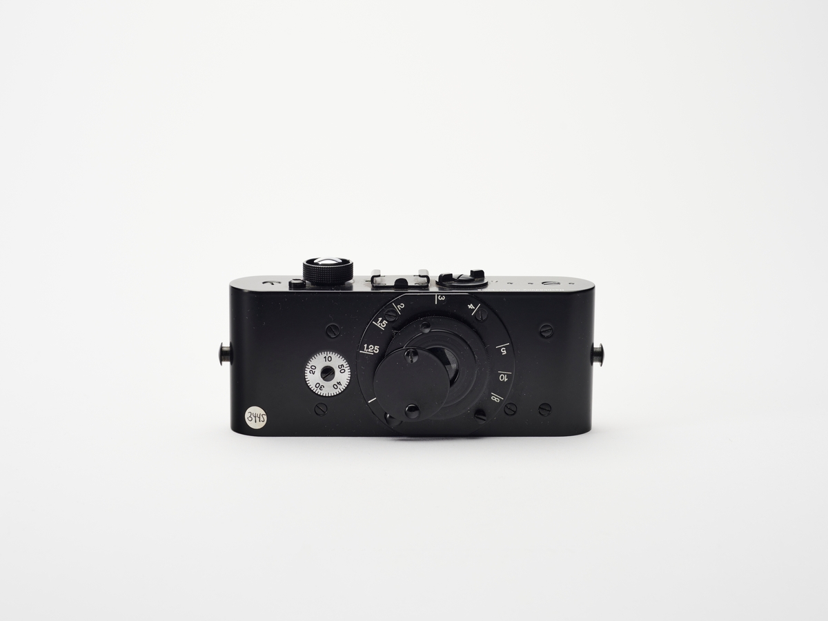 Dette er en Ur-Leica replika. Prototypen ble designet av Oscar Barnack i 1913. Replikaer ble produsert av Leitz slik at bl.a. museer kunne vise og fortelle om dette kameraets betydning for utviklingen innen kamerateknologi og fotohistorie.
Det første Leica-kamera, prototypen Ur-Lecia ble produsert i 1914, men ikke lansert før i 1923, grunnet første verdenskrig. Den første serien ble kalt 0-serie. På denne tiden var kameraene store, tunge og ofte vanskelig å håndtere. Oppfinner og fotograf Oskar Barnack (1879–1936) ved det tyske Ernst Leitz Optische Werke i Wetzlar, var både astmatiker og ivrig fjellklatrer og så derfor et behov for å lage et lettere og enklere kamera. Han klarte å kombinere et lite format med god optikk og konstruerte det som kom til å bli en av de mest populære kameraene gjennom tidene. Negativformatet var en doblet bildebredde på datidens vanlige kinofilm, som var 18 x 24 millimeter. Ved å bruke filmen horisontalt i stedet for vertikalt ble formatet til 24 x 36 millimeter.
Ernst Leitz lanserte Leica 1 på vårmessen i Leipzig i 1924. Navnet Leica er en komibinasjon av av ordene «Leitz» og «Camera». Leica 1 ble tatt godt imot av både amatører og profesjonelle fotografene som Robert Capa, André Kertész og Henri Cartier-Bresson.