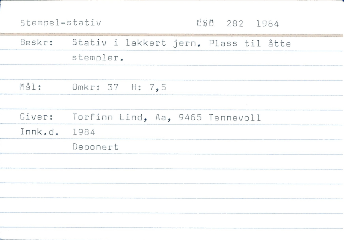 Stempelstativ. Metall. Tidligere sortlakket, rester. Rust. Sirkulær plate med plass til 8 stempel. Metallløkke på toppen. Stang med sirkulær fot. Tallinskrift i bunn.
