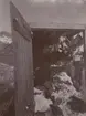 Fotografi från första svenska Antarktisexpeditionen 1901-1904. Motiv av träbyggnad som liknar ett förråd. I förrädet hänger pingvinkött.