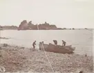 Fotografi från första svenska Antarktisexpeditionen 1901-1904. Motiv av fyra män vid båtar på stenig strand.