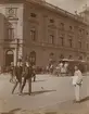 Fotografi från första svenska Antarktisexpeditionen 1901-1904. Motiv av ett antal människor och hästdragen spårvagn på en stor gata i en stad.