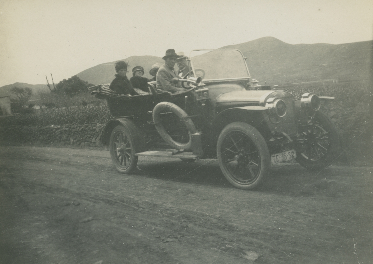 Fotografi från expedition till Peru 1920. Motiv av två män och tre kvinnor i en bil på en grusväg.