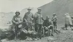 Fotografi från expedition till Peru 1920. Motiv av expeditionsdeltagare som poserar med gevär i ett bergslandskap. Mannen som sitter längst fram kan vara Otto Nordenskjöld.