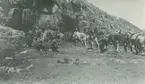 Fotografi från expedition till Peru 1920. Motiv av expeditionsdeltagare till häst nedanför ett berg.