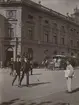 Fotografi från expedition till Peru 1920. Motiv av människor på gata i stad. I bakgrunden syns en hästdragen spårvagn.