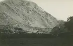 Fotografi från expedition till Peru 1920. Vy över berg. Vid foten av berget ligger ett hus.