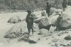 Fotografi från expedition till Peru 1920. Motiv av ett antal personer som står på klippor bredvid flod i djungeln.