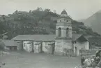 Fotografi från expedition till Peru 1920. Motiv av en kyrka nedanför ett litet berg.