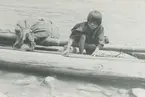Fotografi från expedition till Peru 1920. Motiv av pojke med kanot vid flod.