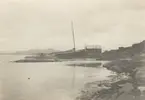 Fotografi från expedition till Spetsbergen. Motiv av en båt som ligger uppdragen på en stenig strand.