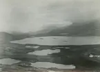 Fotografi från expedition till Östgrönland 1929. Dansk-svensk expedition under ledning av Lauge Koch. Svenska deltagare: Oscar Kulling och Helge Backlund. Vy över ett istäckt bergslandskap och molnprydd himmel.