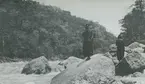 Fotografi från expedition till Peru 1920. Motiv av två män som står på klippor vid flod i djungeln.