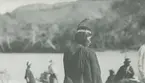 Fotografi från expedition till Peru 1920. Motiv av man med fjäder i håret i djungeln.