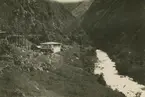 Fotografi från expedition till Peru 1920. Motiv av hus och flod i ett bergslandskap.