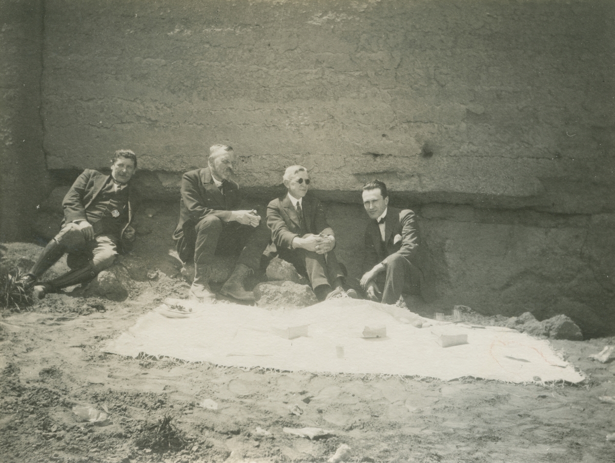 Fotografi från expedition till Peru 1920. Motiv av fyra expeditionsdeltagare sittande vid stenvägg. Mannen näst längst till vänster är Otto Nordenskjöld.