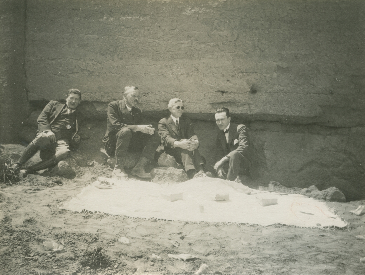 Fotografi från expedition till Peru 1920. Motiv av fyra expeditionsdeltagare sittande vid stenvägg. Mannen näst längst till vänster är Otto Nordenskjöld.