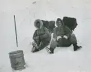 Fotografi från låda märkt Bernt Balchen. Balchen var norsk-amerikansk flygare, polarforskare och militär. Motiv av två män i vinterkläder och med packning på ryggarna framför igloo.