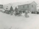 Fotografi från låda märkt Bernt Balchen. Balchen var norsk-amerikansk flygare, polarforskare och militär. Motiv av Bernt Balchens hundspann i snön vid hus.