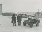 Fotografi från låda märkt Bernt Balchen. Balchen var norsk-amerikansk flygare, polarforskare och militär. Motiv av två vinterklädda män i snön vid jeep framför hus.