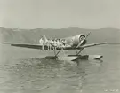 Fotografi från låda märkt Bernt Balchen. Balchen var norsk-amerikansk flygare, polarforskare och militär. Motiv av fyra män och två kvinnor som sitter på flygbåtsvinge.