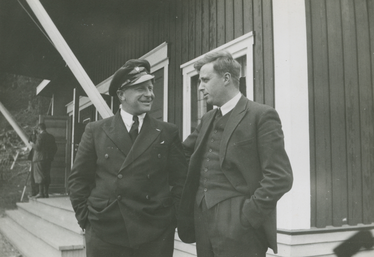 Fotografi från låda märkt Bernt Balchen. Balchen var norsk-amerikansk flygare, polarforskare och militär. Motiv av Balchen och annan man utanför hus.