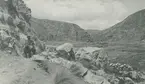 Fotografi från Peruexpedition 1920. Motiv av man som rider på häst i ett kargt bergslandskap.