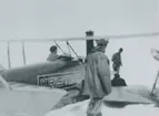 Fotografi från svenska undsättningsexpeditionen 1928. Motiv av tre män och ett flygplan.