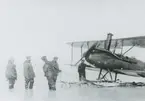 Fotografi från svenska undsättningsexpeditionen 1928. Motiv av fem män och ett flygplan.