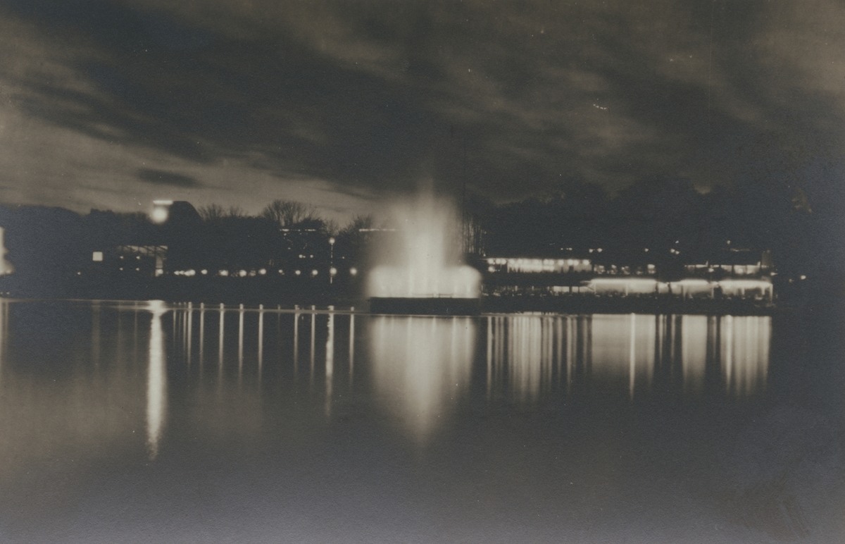 Fotografi från Stockholmsutställningen 1930. Motiv av fontän och dramatisk himmel.