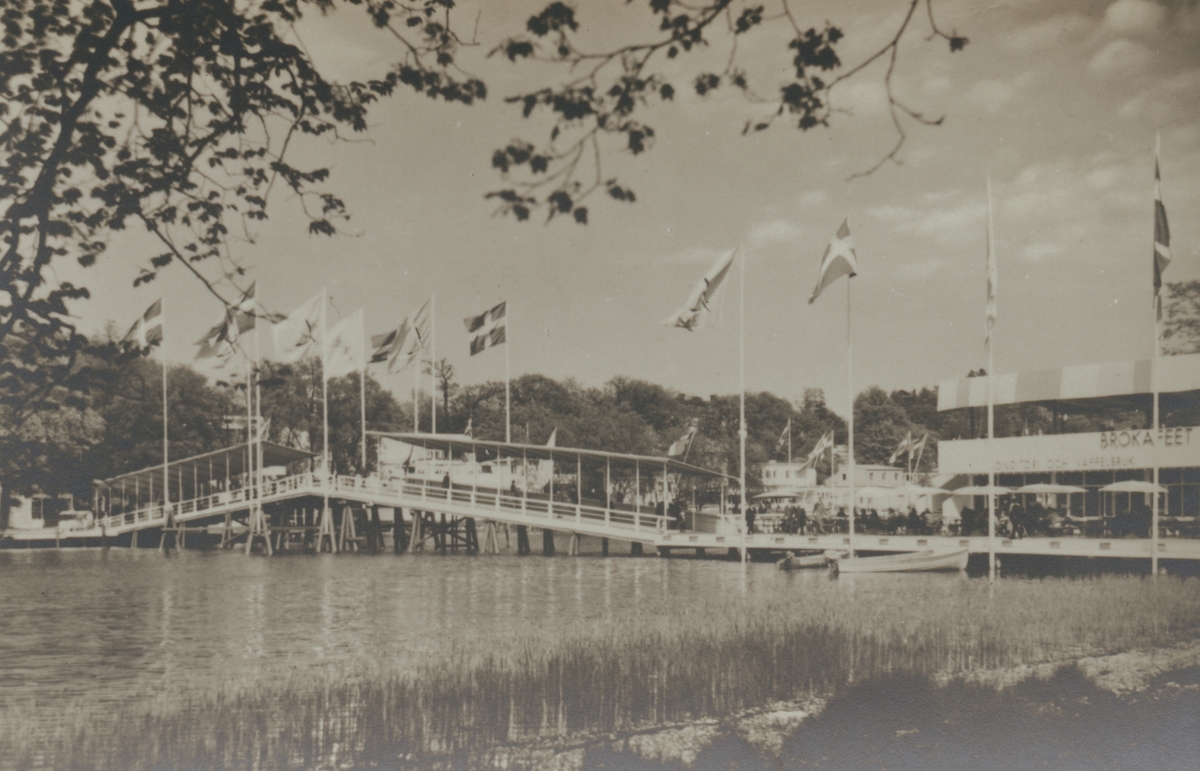 Fotografi från Stockholmsutställningen 1930. Motiv av bro, brokafé och flaggor.